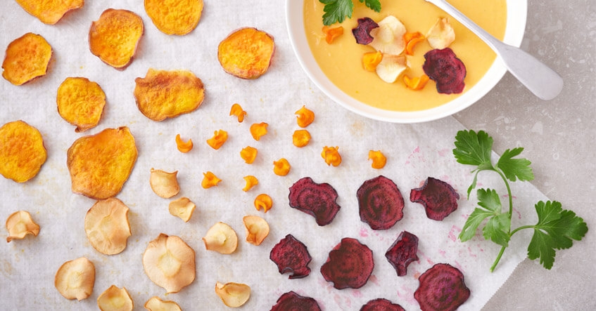 Chips de verduras con chirivía, boniato, zanahoria y remolacha sobre papel de horno Albal®, con bol de crema de boniato.