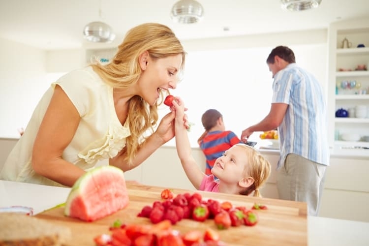 Familia feliz preparando el postre con fresas y sandía.